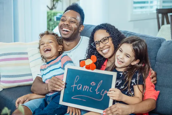 A warm, inviting illustration of a multi-generational family sitting together on a cozy living room couch, engaged in heartfelt conversation.
